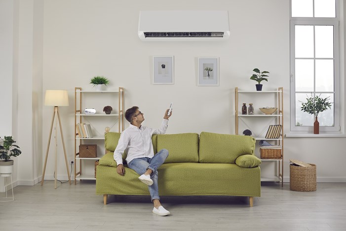 Man switching heat pump setting while relaxing at home